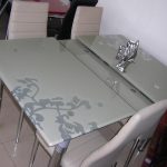 Les piétements et les pieds des tables en verre sont le plus souvent en chrome ou en bois.