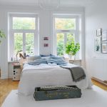 Chambre blanche avec tête de lit à deux fenêtres