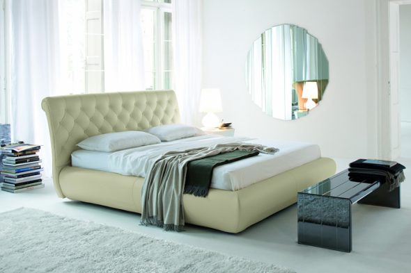 Un lit avec une tête de lit haute et douce, situé à distance de la fenêtre
