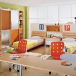 Chambre pour deux adolescents avec des lits près de la fenêtre avec un grand bureau pour deux