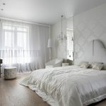 Un grand lit avec une tête de lit blanche et un couvre-lit en soie blanche