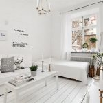 Salon blanc avec meubles blancs le long d'un mur.