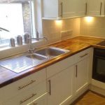 Cocina blanca con encimera de madera natural.
