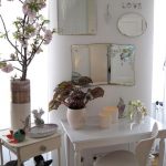 Une petite table blanche avec des miroirs de différentes tailles