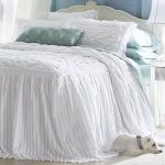 Couvre-lit allongé blanc comme neige sur le lit