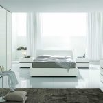 Chambre blanche moderne avec un lit près de la fenêtre panoramique