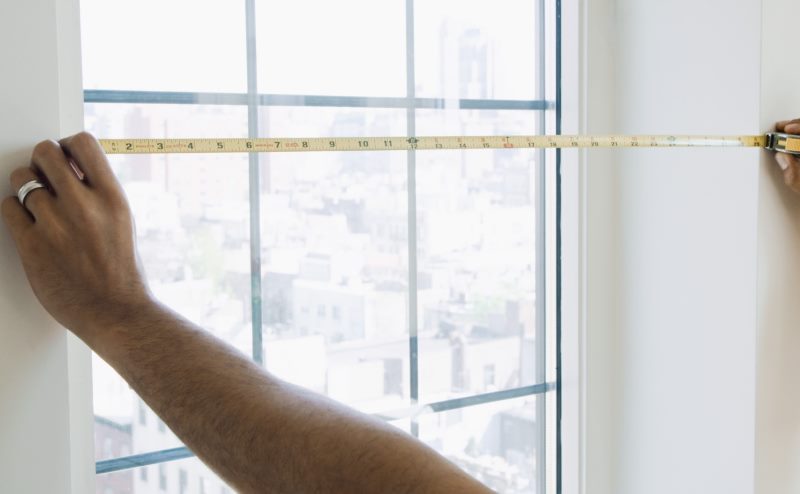 Mesure d'une ouverture de fenêtre avec un ruban à mesurer en métal avec vos propres mains