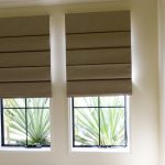 Cascadas cortinas romanas en ventanas estrechas en el interior