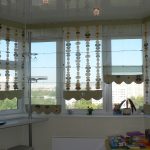 Persianas romanas combinadas transparentes y estampadas en la ventana de la bahía