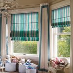 Cortinas romanas a rayas para una amplia sala infantil.