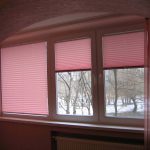 Ciechi pieghettati rosa sul balcone in un appartamento di tre stanze