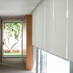 Weiße Rollläden auf einem großen Fenster in einem schmalen Korridor