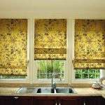 Cortinas estampadas florales doradas romanas para la ventana de la cocina.