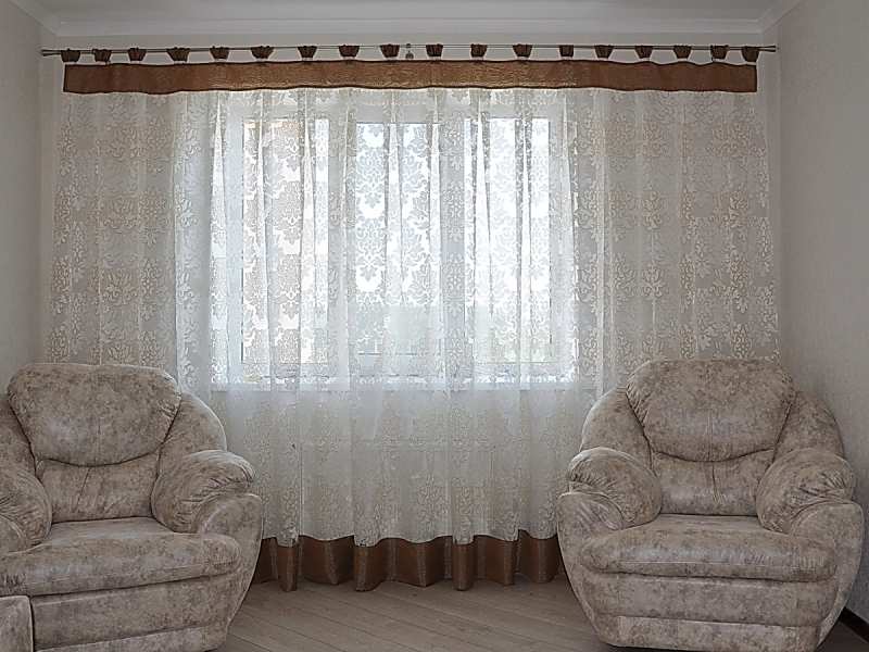 Deux chaises devant une fenêtre avec tulle