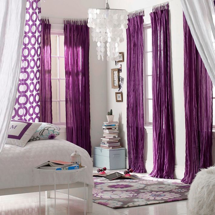 Cortinas moradas en el interior del dormitorio blanco.