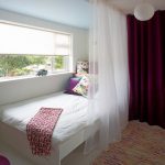 Cama de bebé frente a la ventana en el dormitorio.