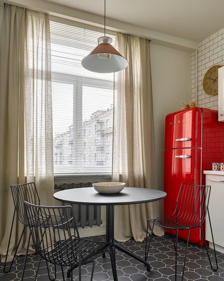 Red fridge near the kitchen window with light curtains