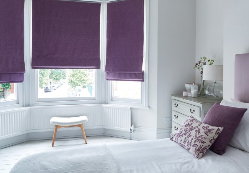 Dormitorio blanco con matices romanos de tonos morados.