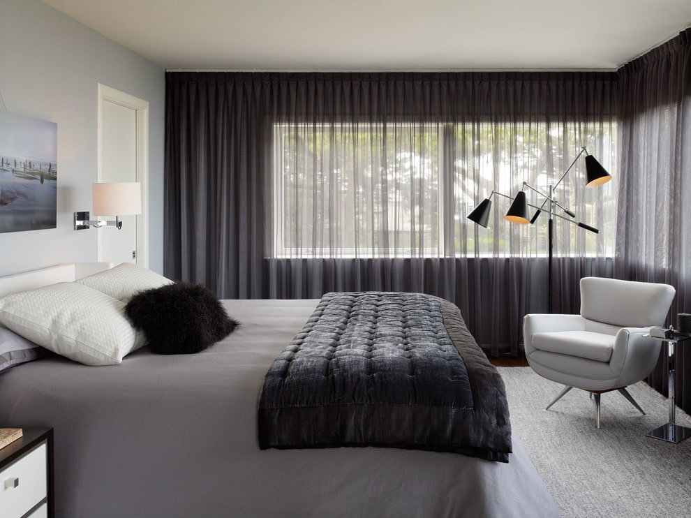 Tulle gris sur la fenêtre de la chambre à coucher avec une fenêtre sur le côté sud de la maison