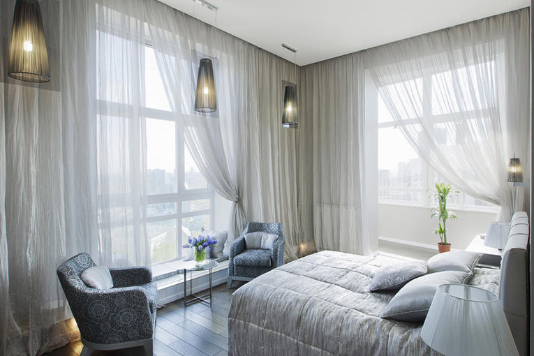 Rideaux de lumière sur de grandes fenêtres dans la chambre d'angle