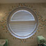 Round window of two parts in the bathroom, closed by blinds