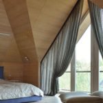 Chic curtains on the triangular window in the bedroom in the attic