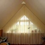 Curtains on the whole wall with a triangular window