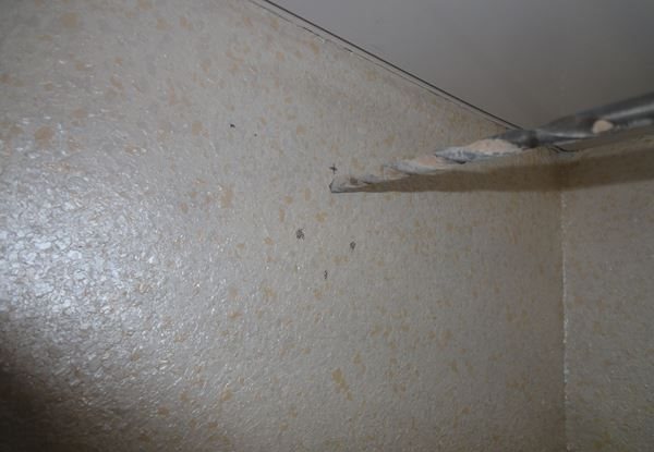 Percer des trous dans le mur pour les avant-toits avec des rideaux