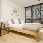 Lit en bois dans la chambre avec stores aux fenêtres