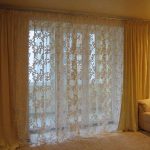 Voile avec ornement crème sur la fenêtre dans le hall