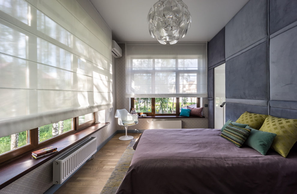Rideaux romains en tissu léger sur les grandes fenêtres de la chambre