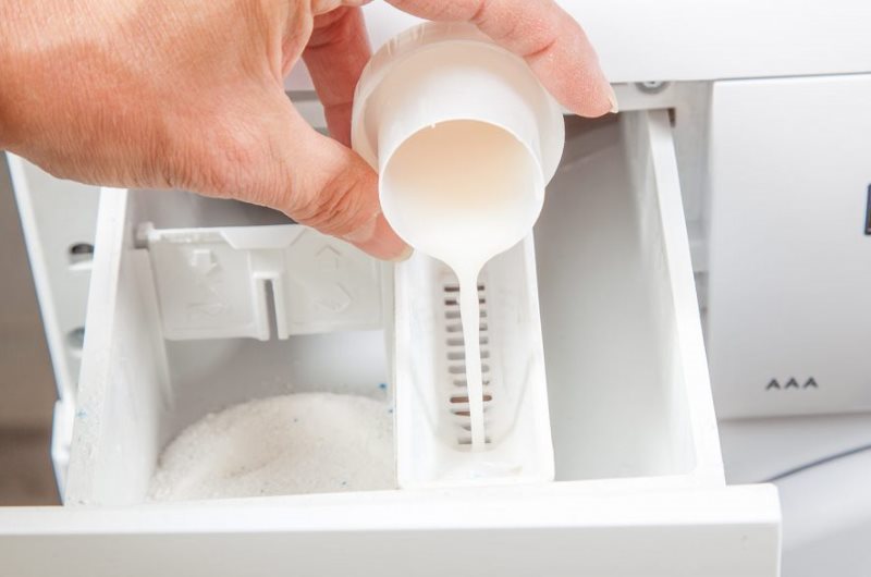 Pouring bleach gel into the washing machine compartment